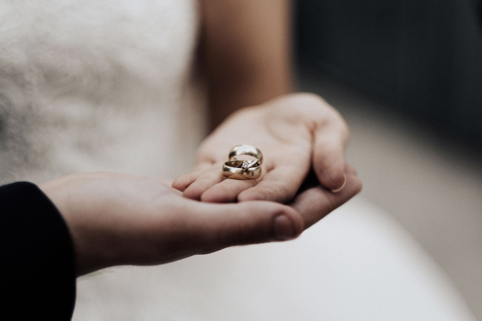 Two hands and wedding rings resting on a table, symbolizing the commitment and structure Saturn brings to synastry
