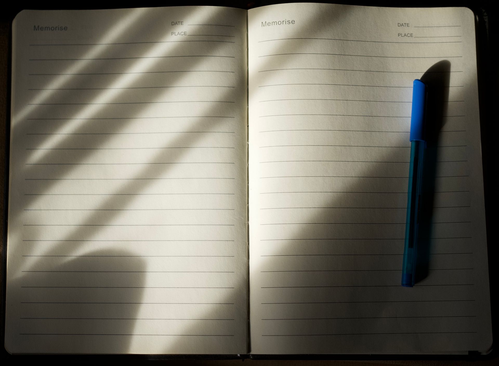 An open lined notebook with a pen resting on it under soft natural light