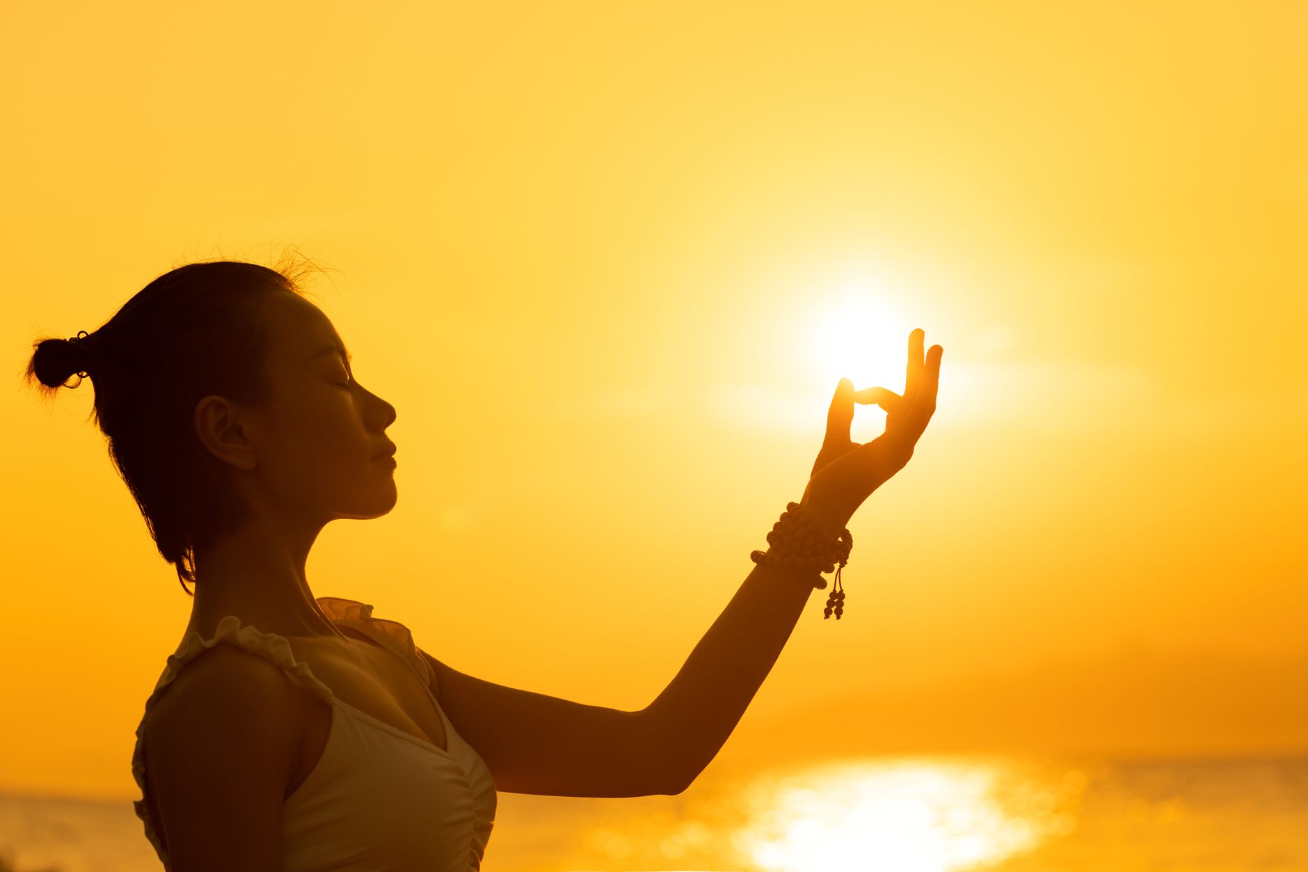 Seven glowing energy points aligned along a meditating silhouette at sunset