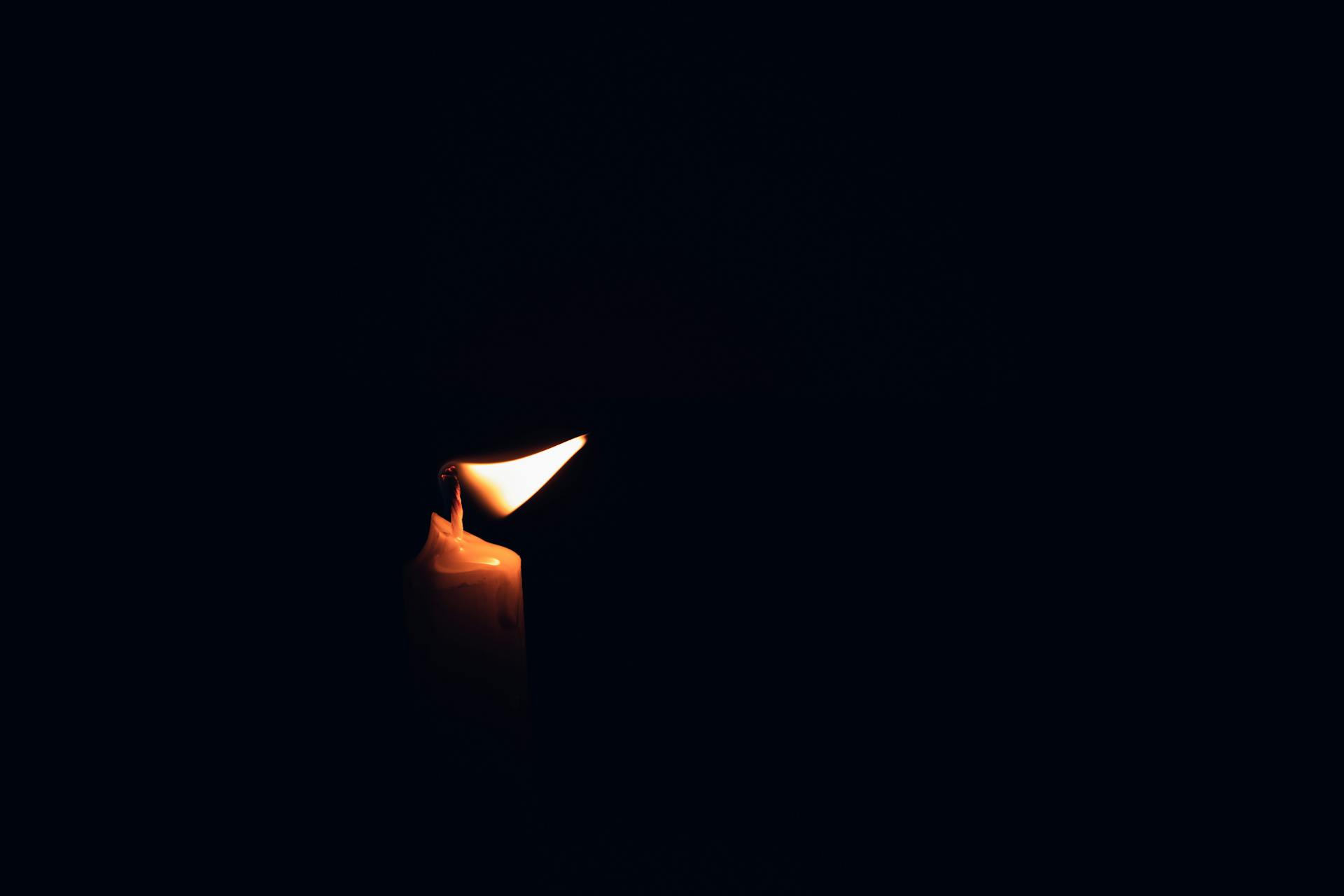 Person sitting in meditation surrounded by soft candlelight in a dark room representing introspection and inner work