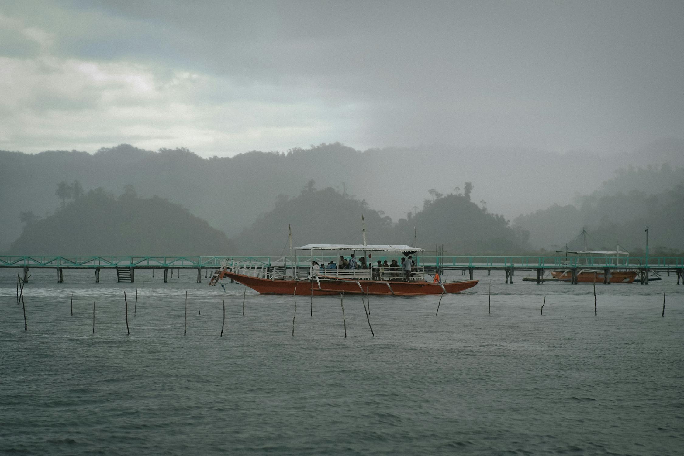 A boat navigating through misty waters near lush fog-covered hills evoking the quiet journey toward calmer shores that defines the Six of Swords