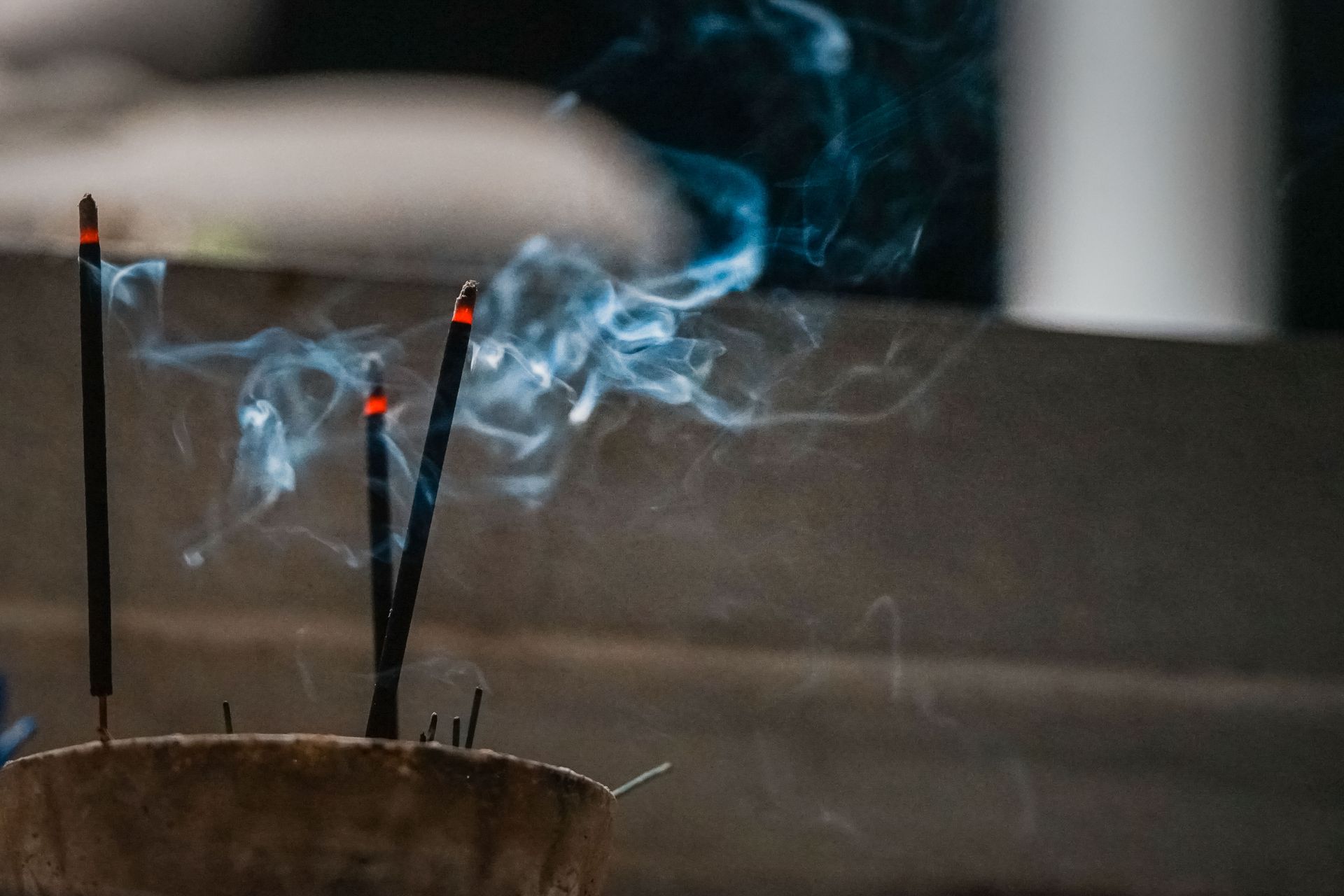 Soft incense smoke curling upward in a calm, softly lit room