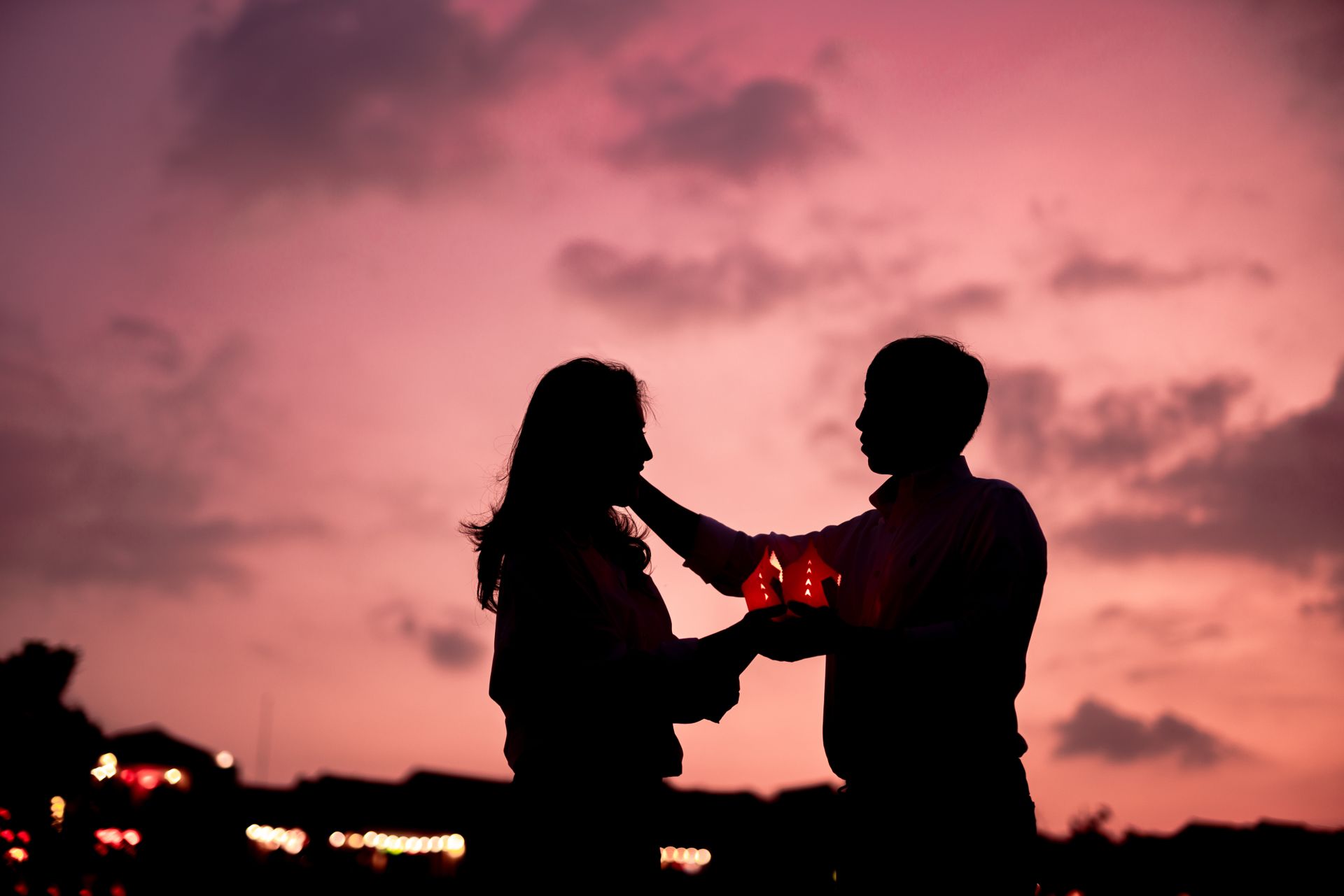 A couple in silhouette holding lanterns at sunset, symbolizing the deep bond behind the soulmate vs twin flame connection