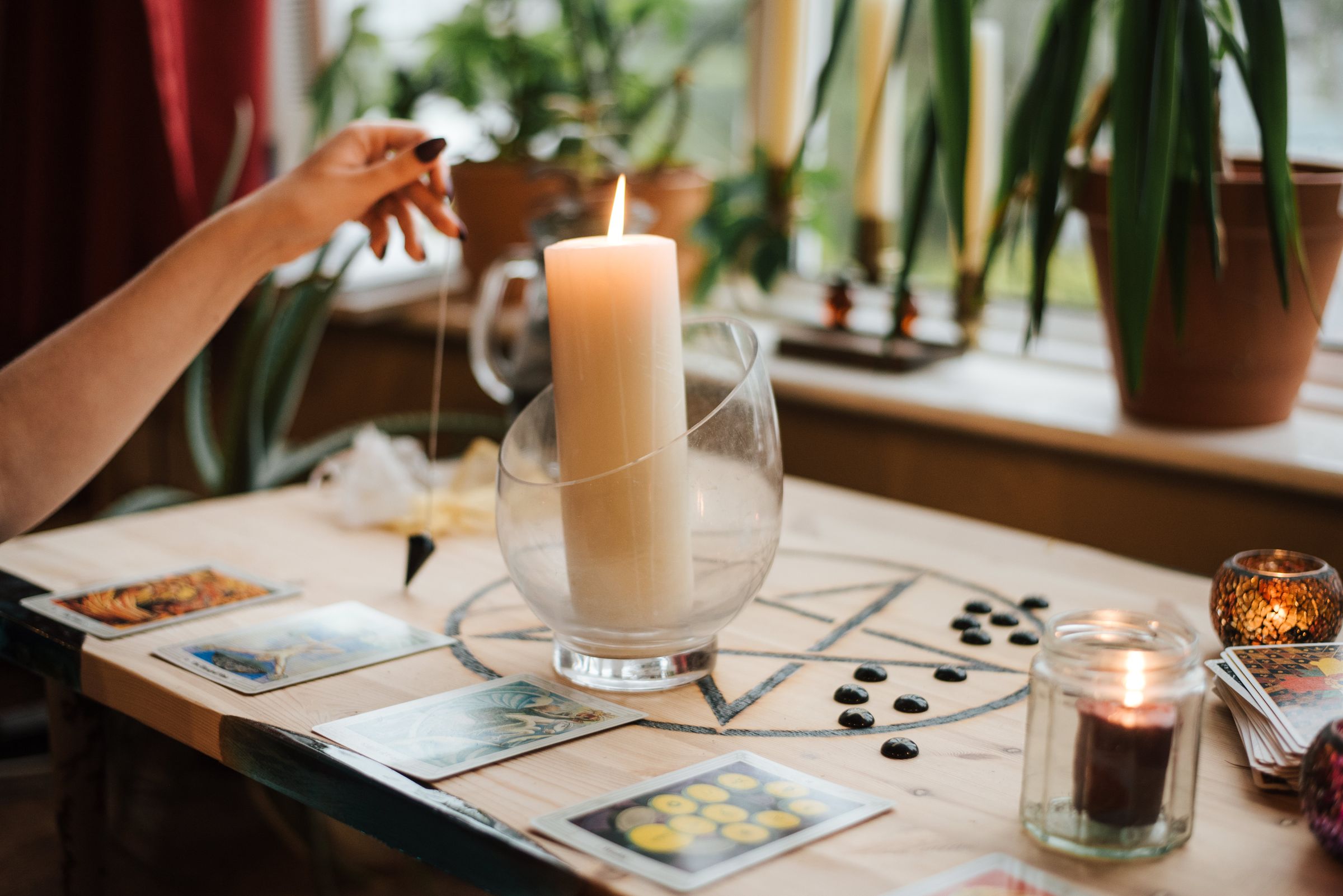 Hands of a reader at a candlelit table with tarot cards laid out for a birth card calculation