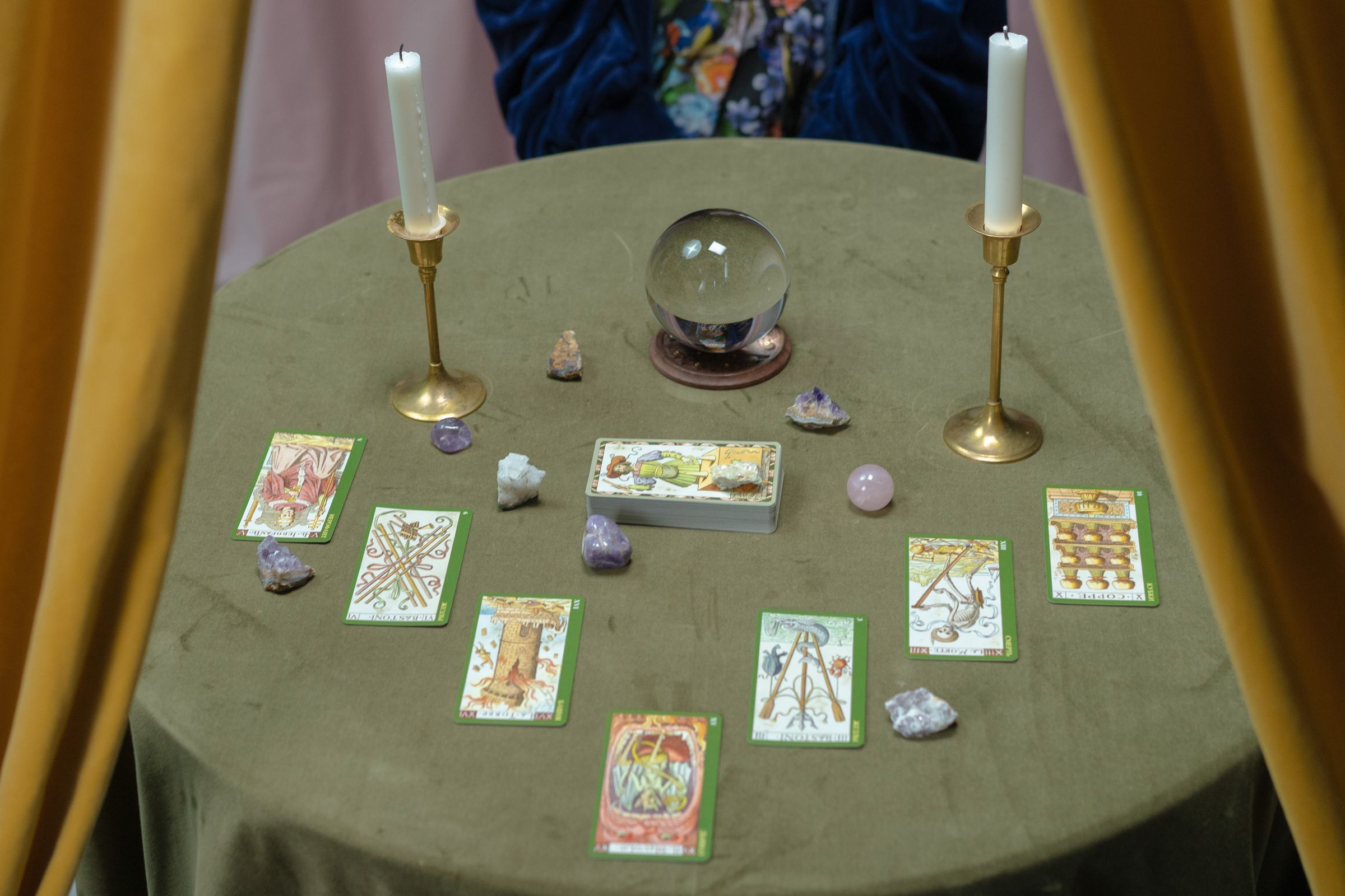 Tarot cards beside crystals and a crystal ball arranged on a reading table