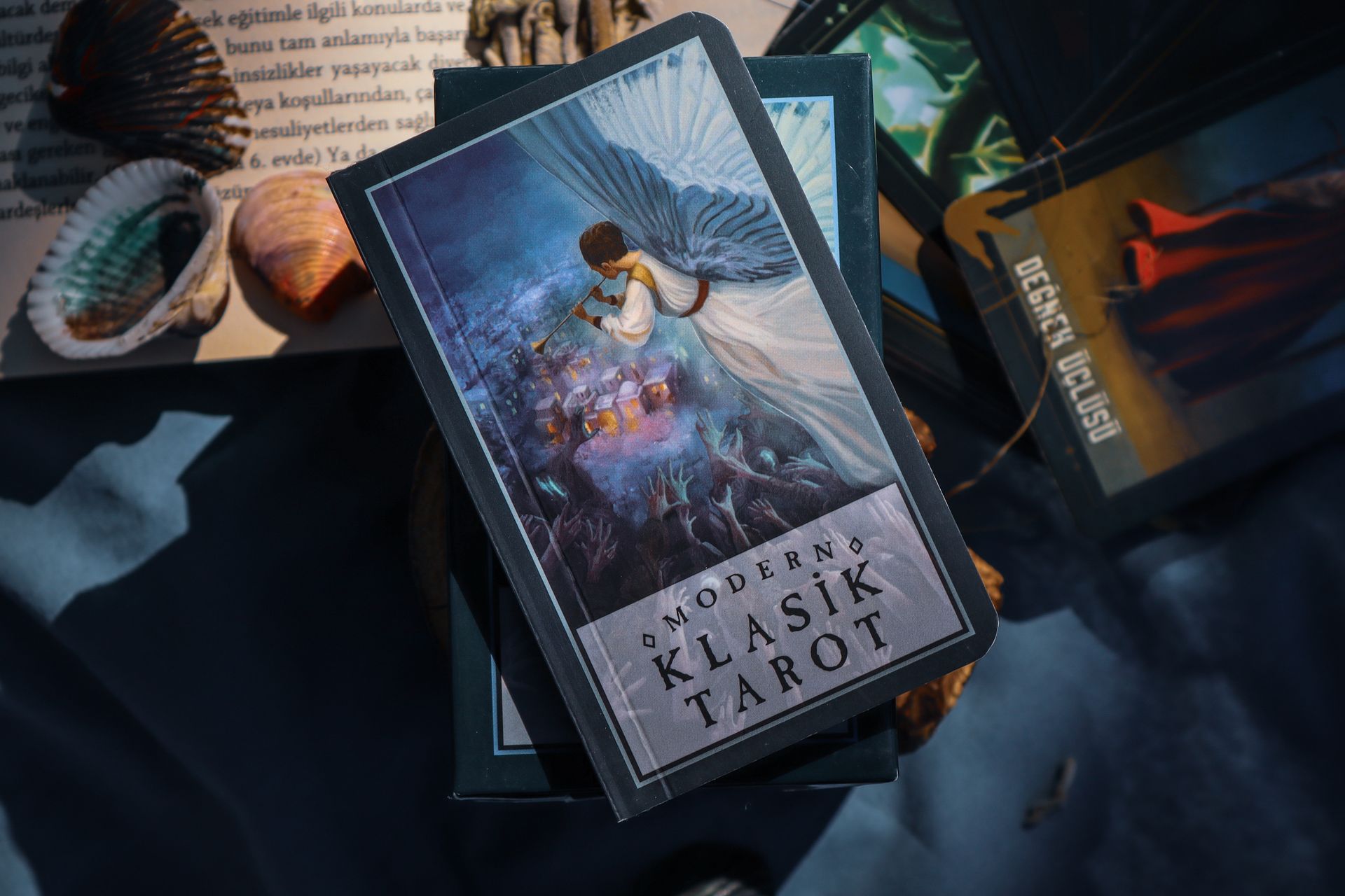 A mystical tarot deck fanned out near dried flowers and crystals on a wooden surface