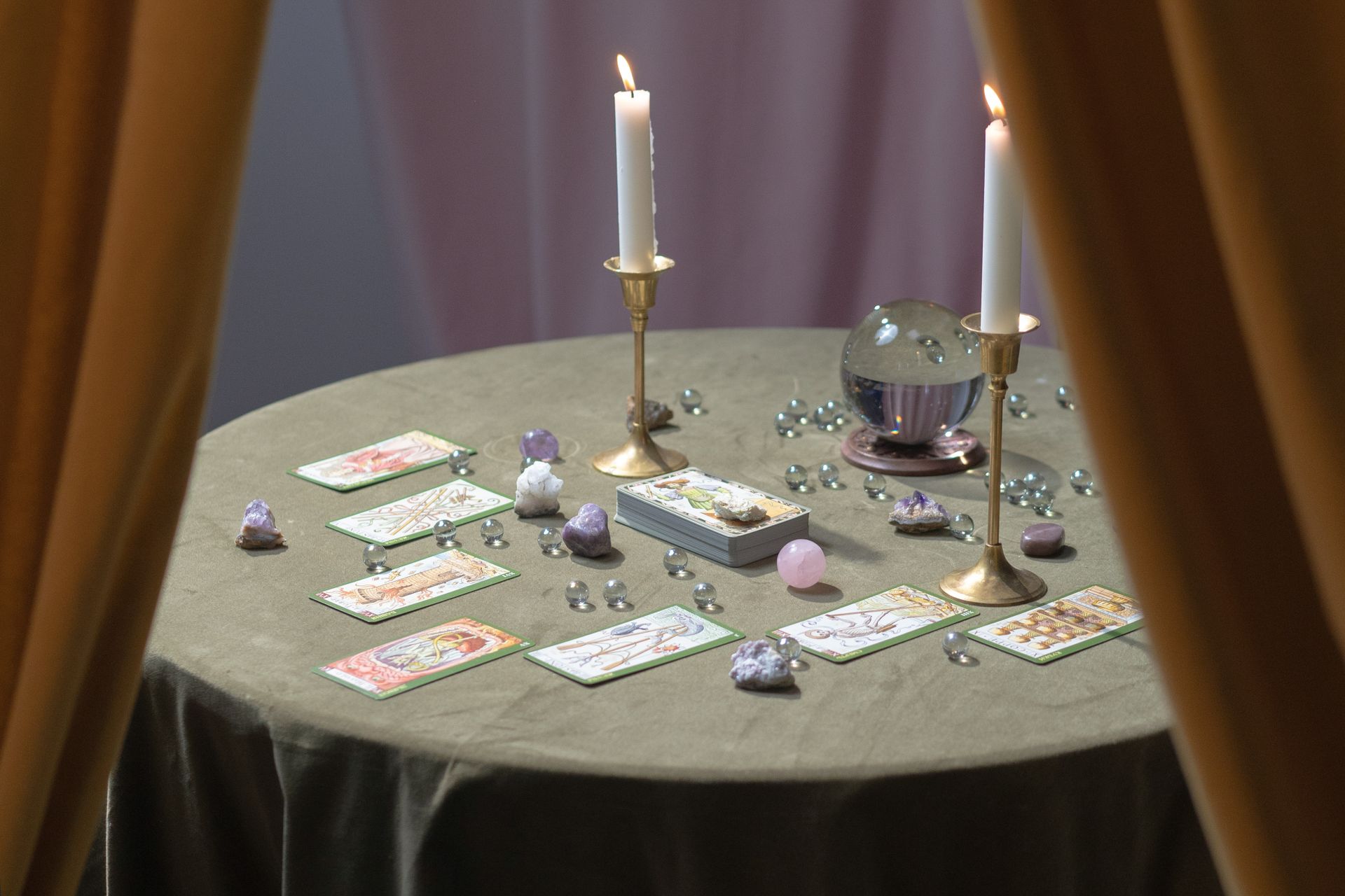 Hands turning over tarot cards on a cloth-covered reading table by soft light