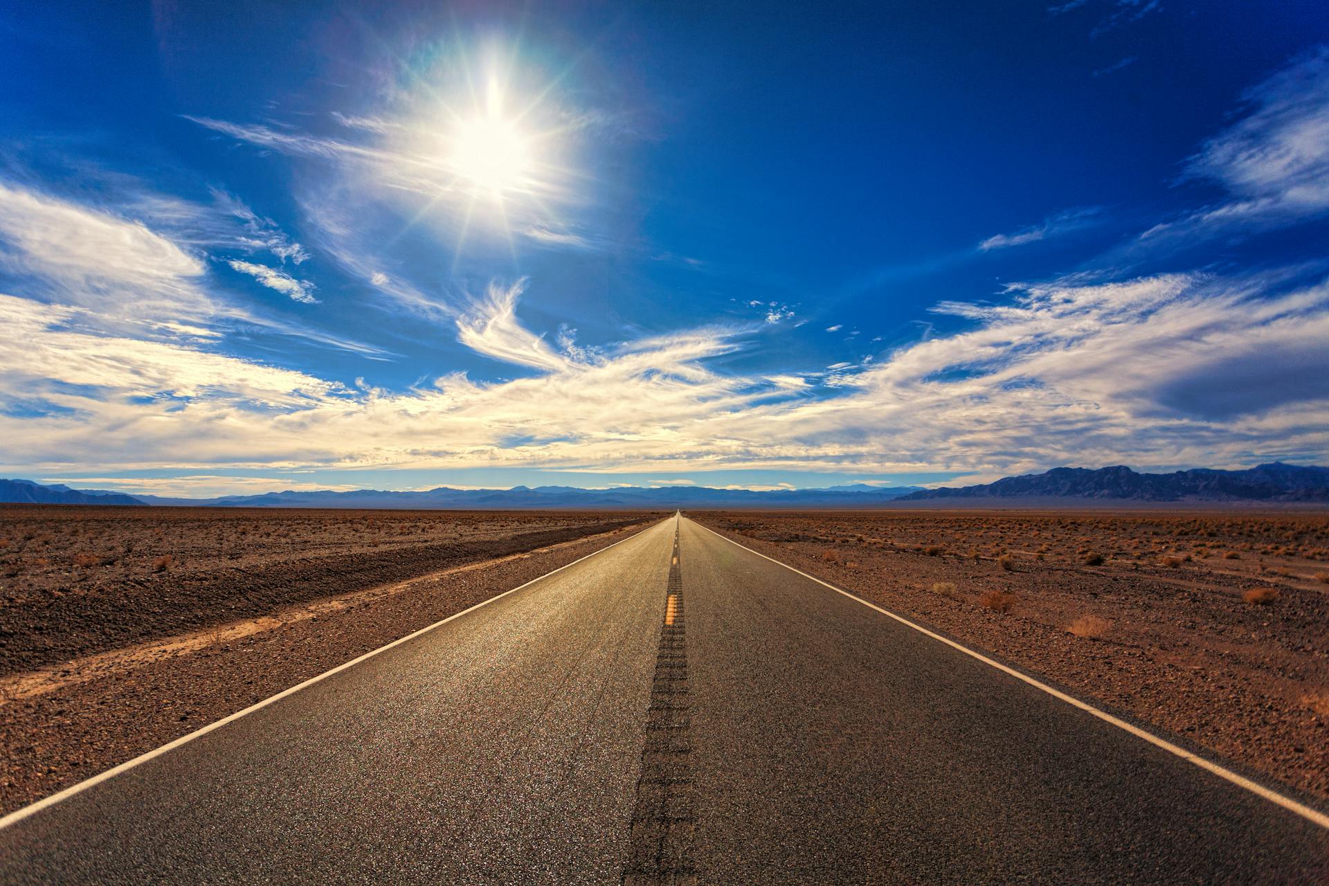 A long straight road stretching across a desert landscape under a bright sky symbolizing the determined journey ahead