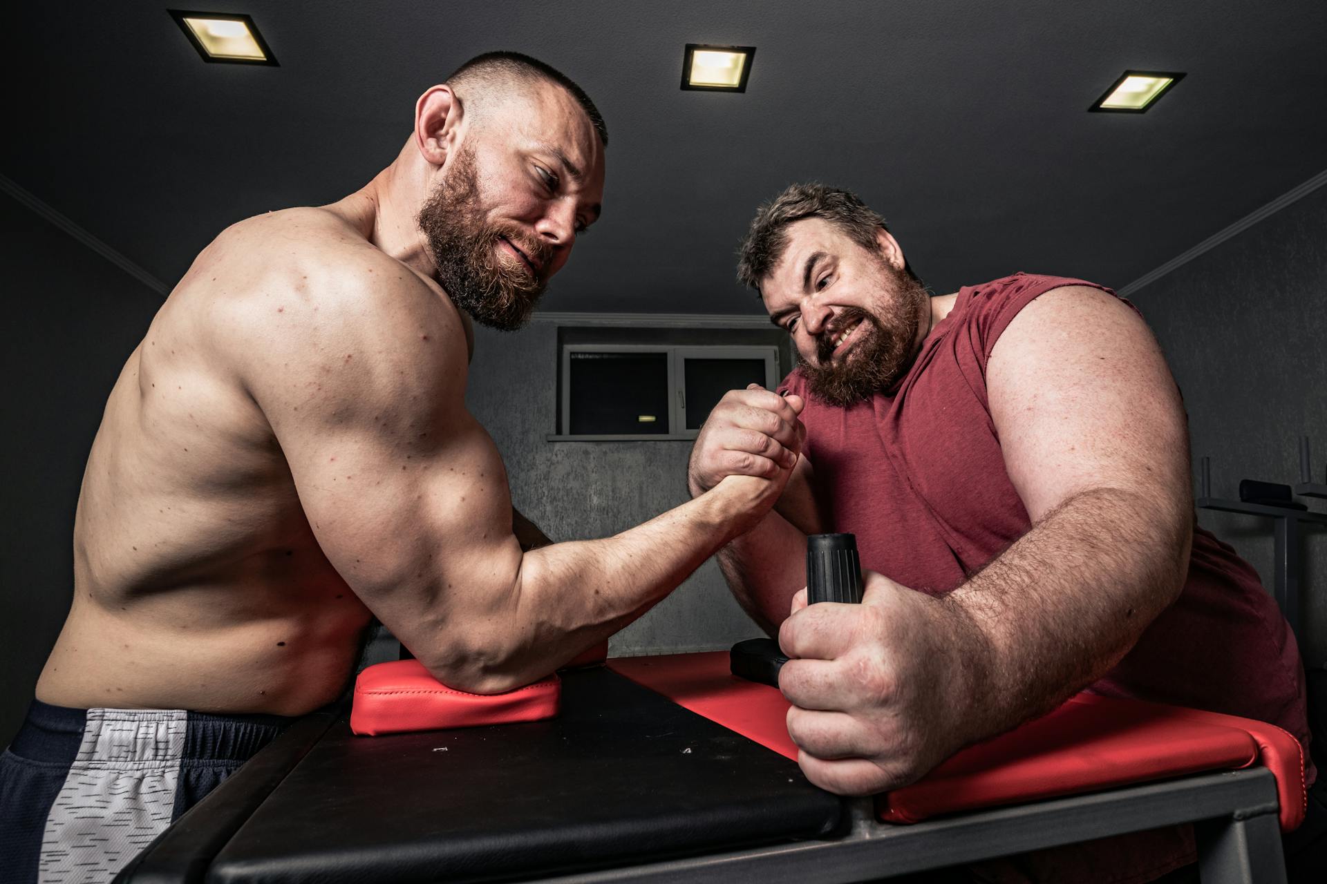Two muscular men competing in an intense arm wrestling match showcasing the strength and determination at the heart of the Five of Wands