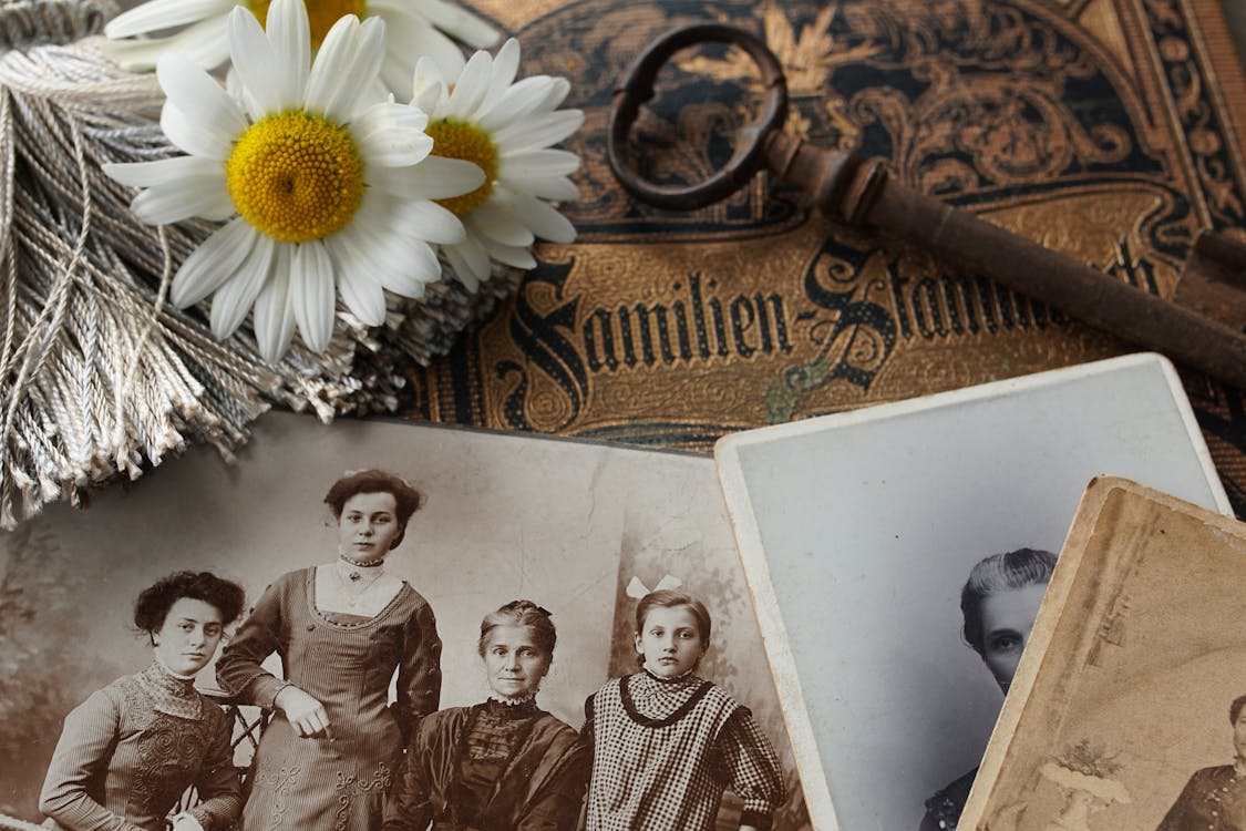 Vintage family photographs with daisies and an antique key evoking the warmth of cherished memories and the nostalgic pull of the past that defines the Six of Cups
