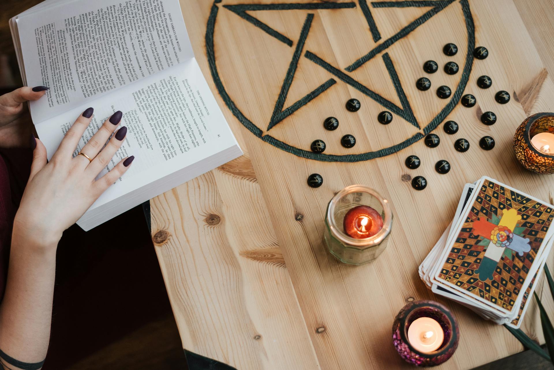 A fortune teller reading tarot cards at a table with candles during a divination session