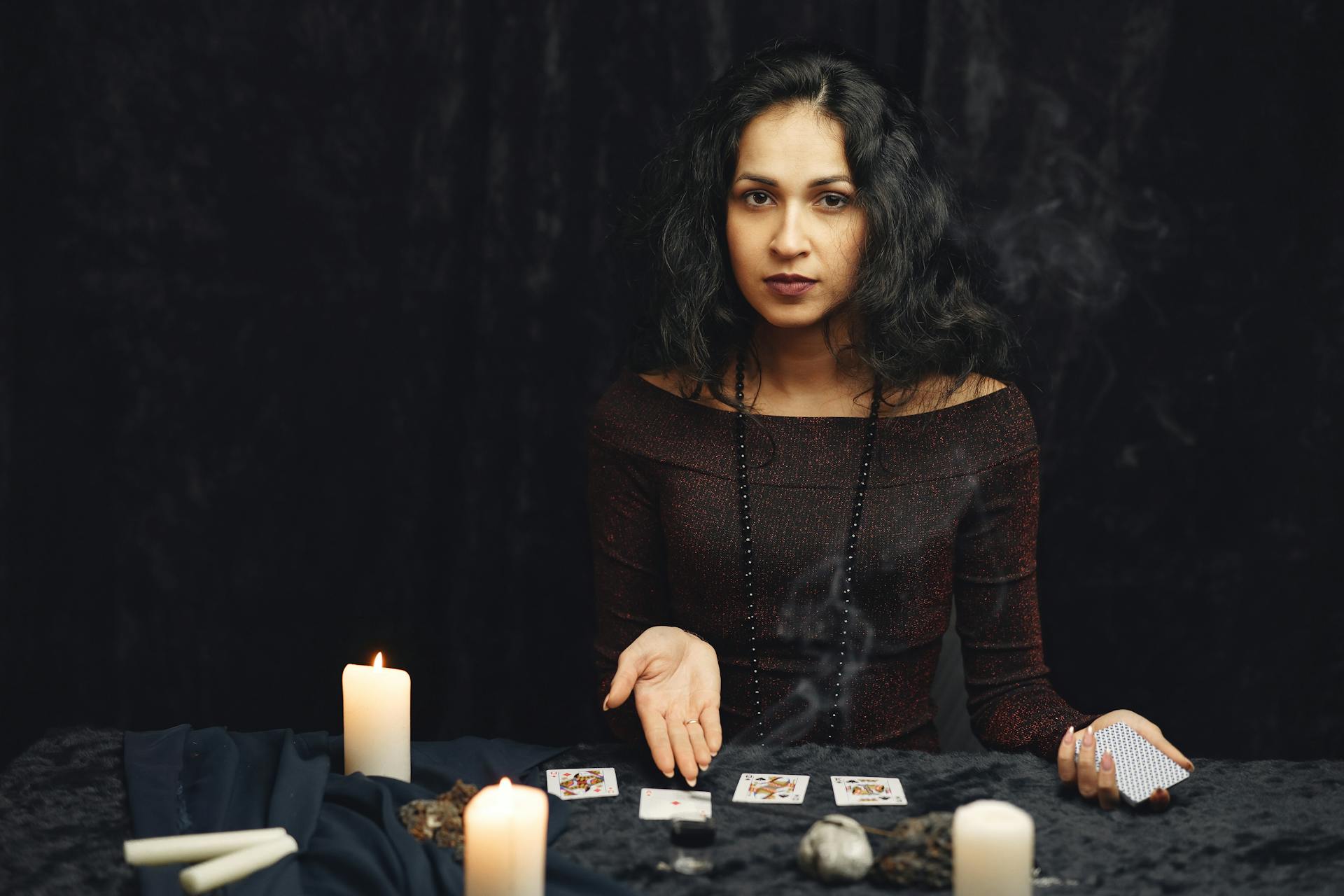 A tarot reading laid out by candlelight with a notebook nearby, representing steady practice with the four suits