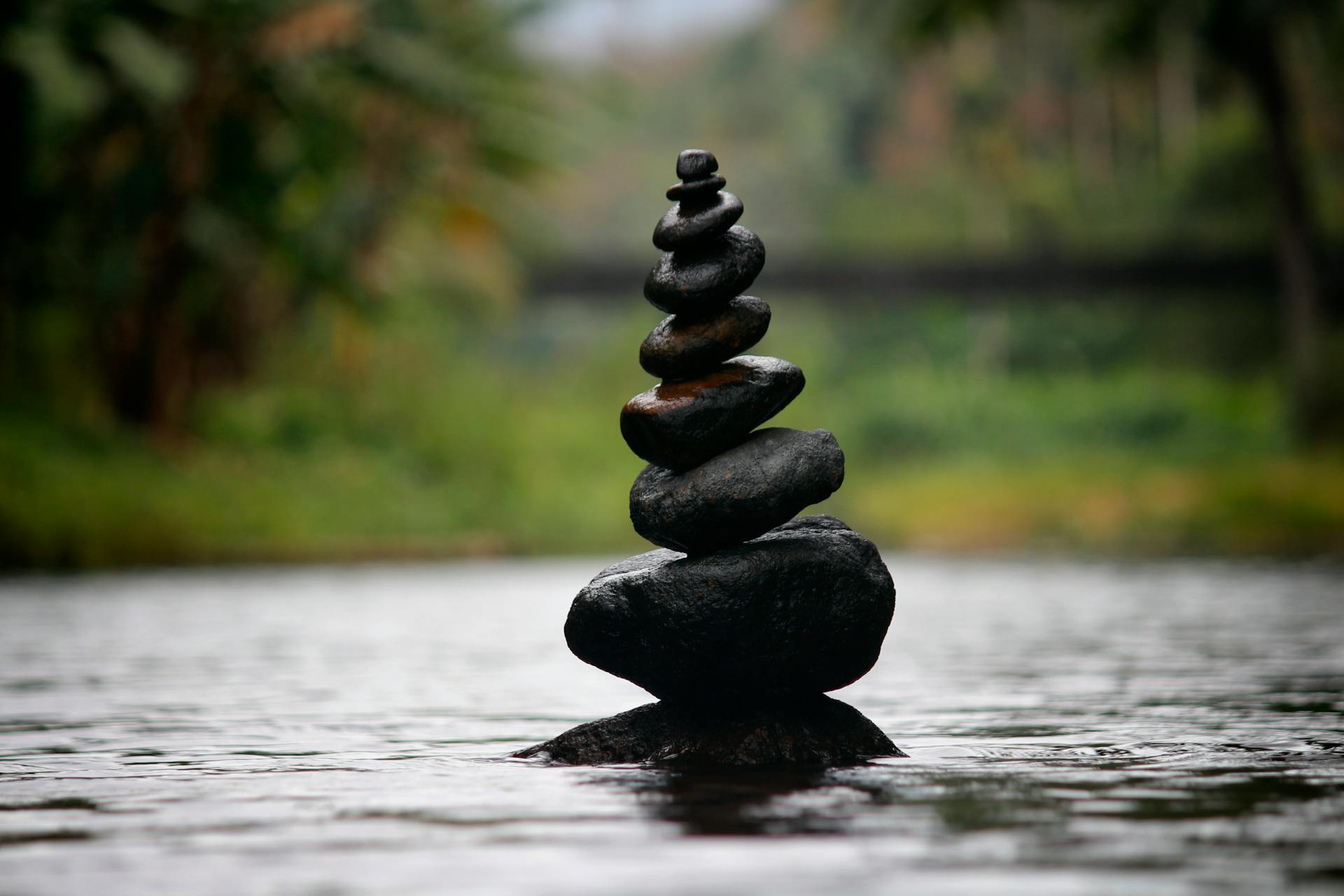 Balanced stones in a serene river evoking the peace and harmony that Temperance brings after transformation