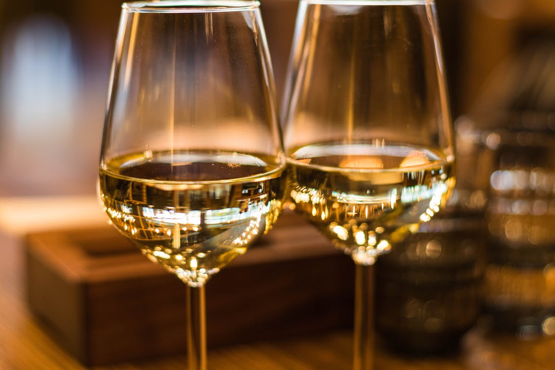 Two elegant wine glasses filled with white wine captured with beautiful bokeh light reflecting the balanced reciprocal exchange at the heart of the Two of Cups