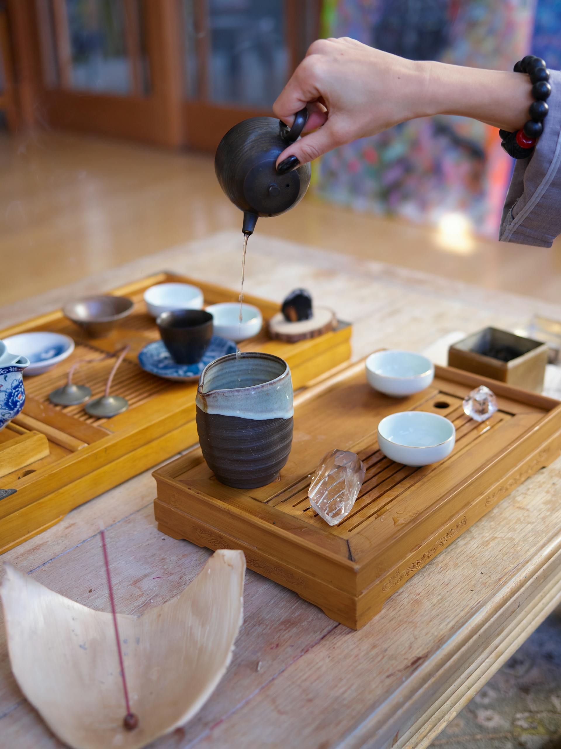 A serene tea ceremony setup with ceramic cups incense and crystals on wooden trays creating a meditative atmosphere for divination