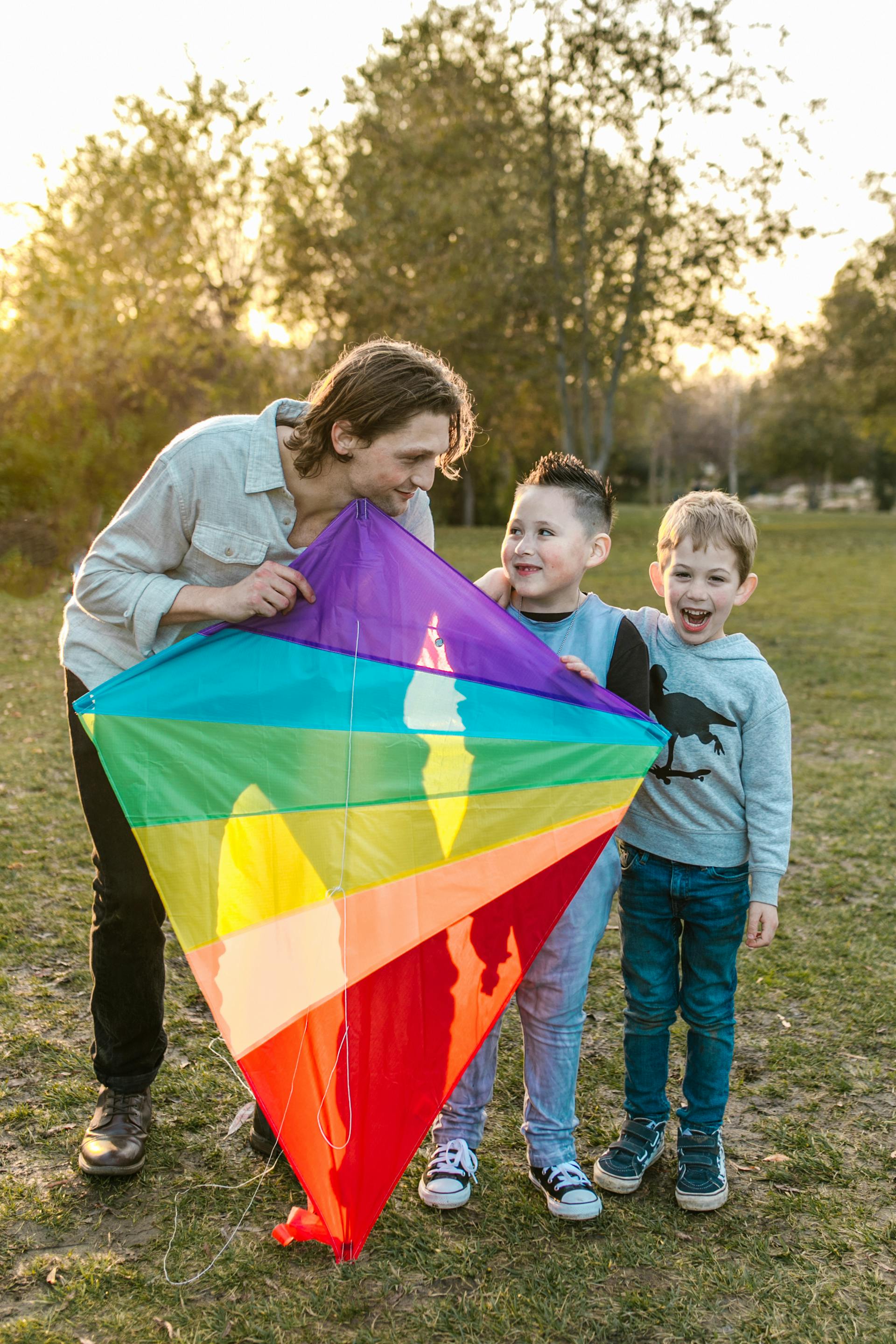A joyful father and his sons flying a rainbow kite in a sunny park capturing the shared happiness and family connection of the Ten of Cups