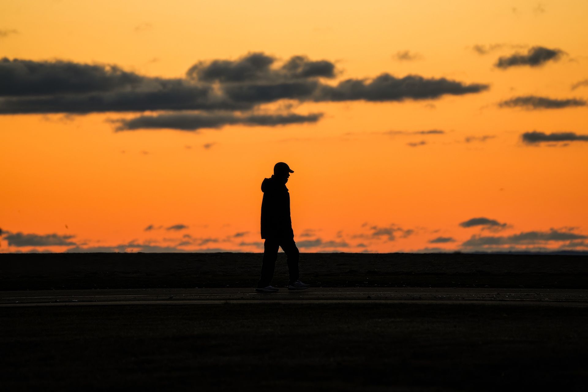 Lone figure walking against a vivid sunset sky, representing the awakening and life redirection of the Uranus opposition midlife transit
