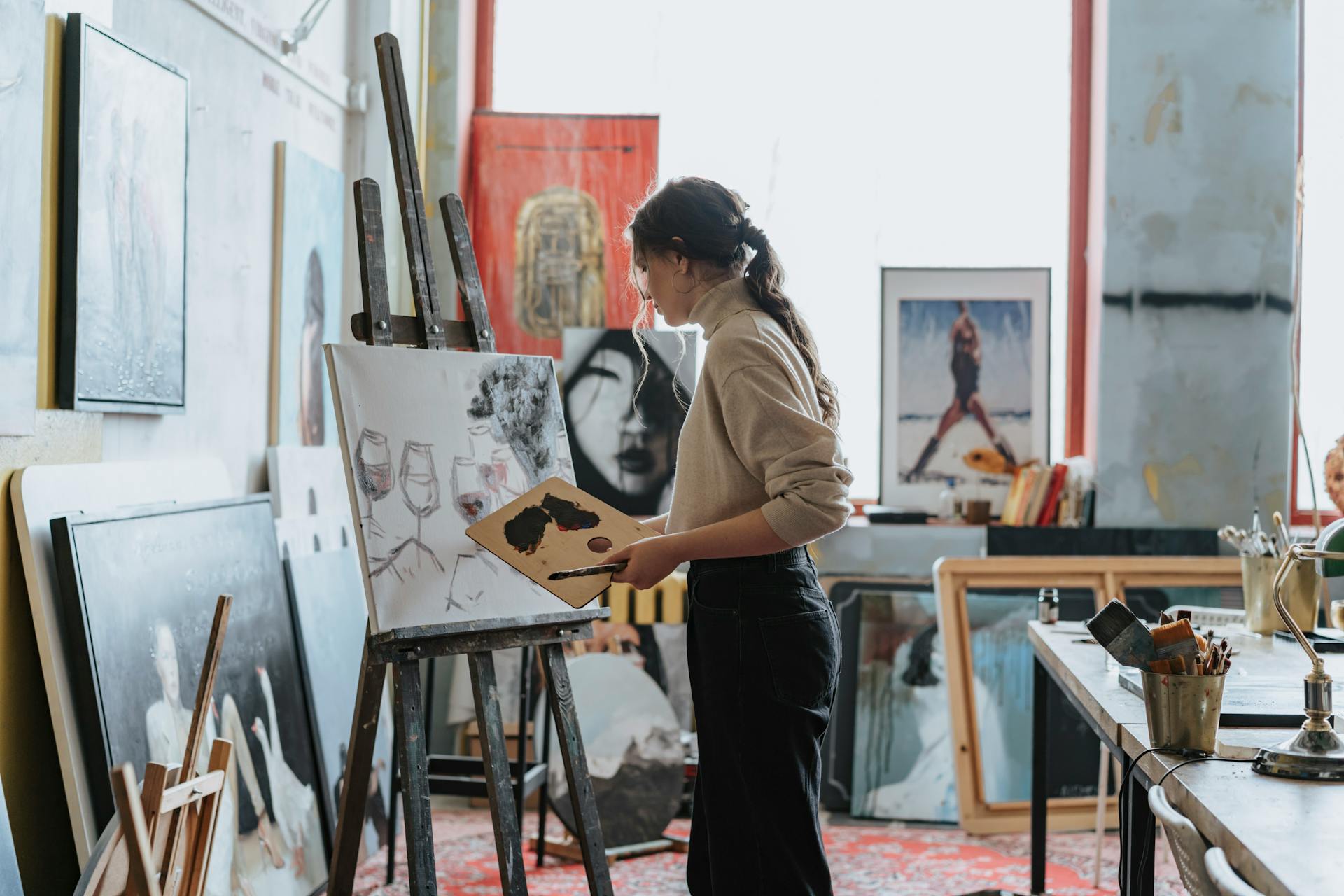 A woman artist working on a painting in a creative studio filled with natural light representing Venus creative expression