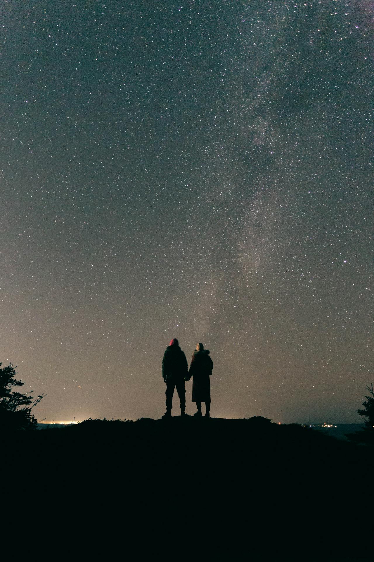 Romantic silhouette of a couple under a vast star-filled night sky reflecting the themes of love and cosmic connection