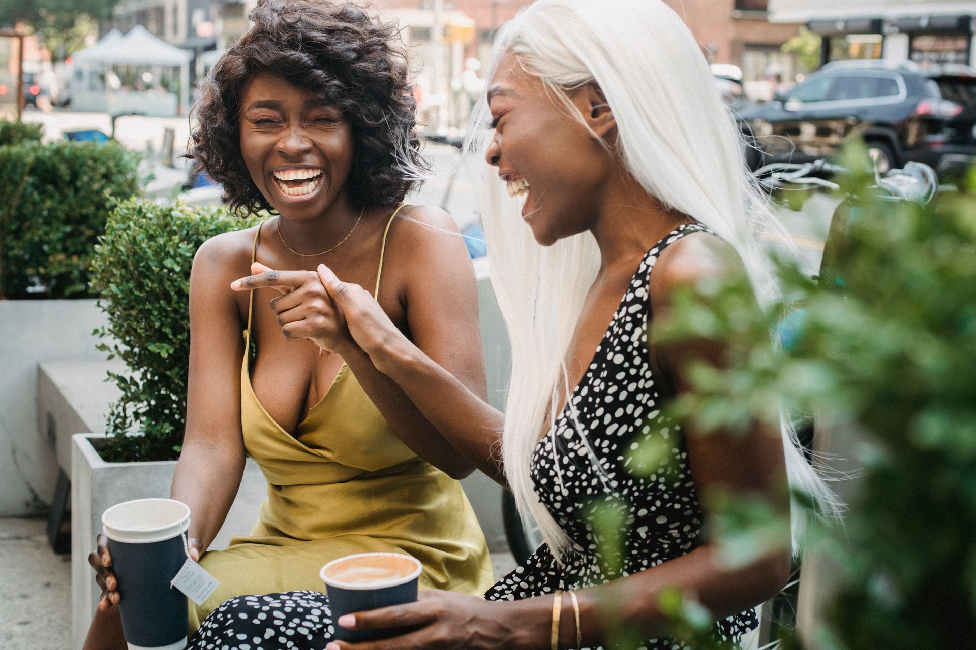 Two close friends laughing together over coffee, showing the easy warmth of a compatible zodiac friendship