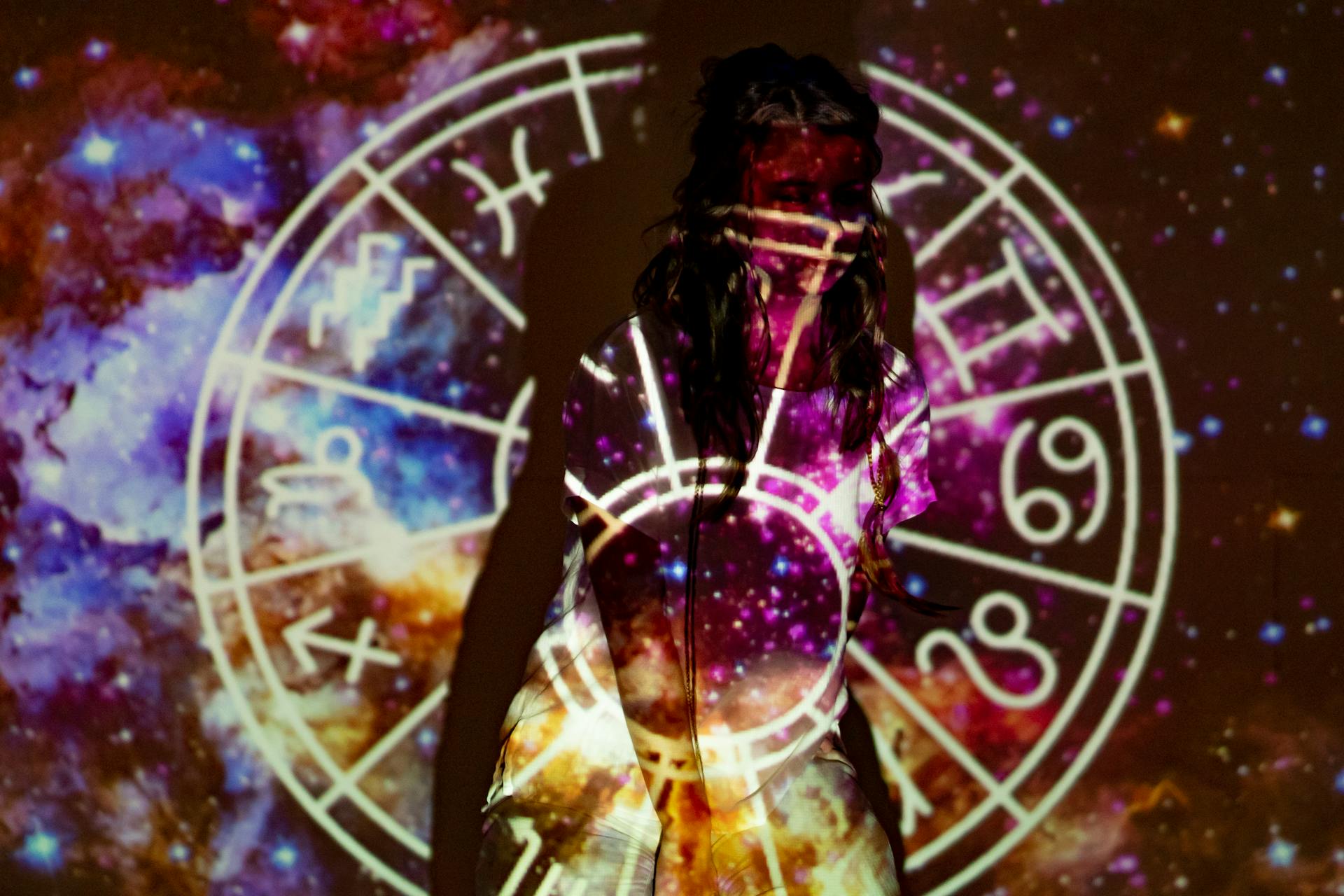 A mystical image of a woman enveloped in celestial projections and astrological symbols